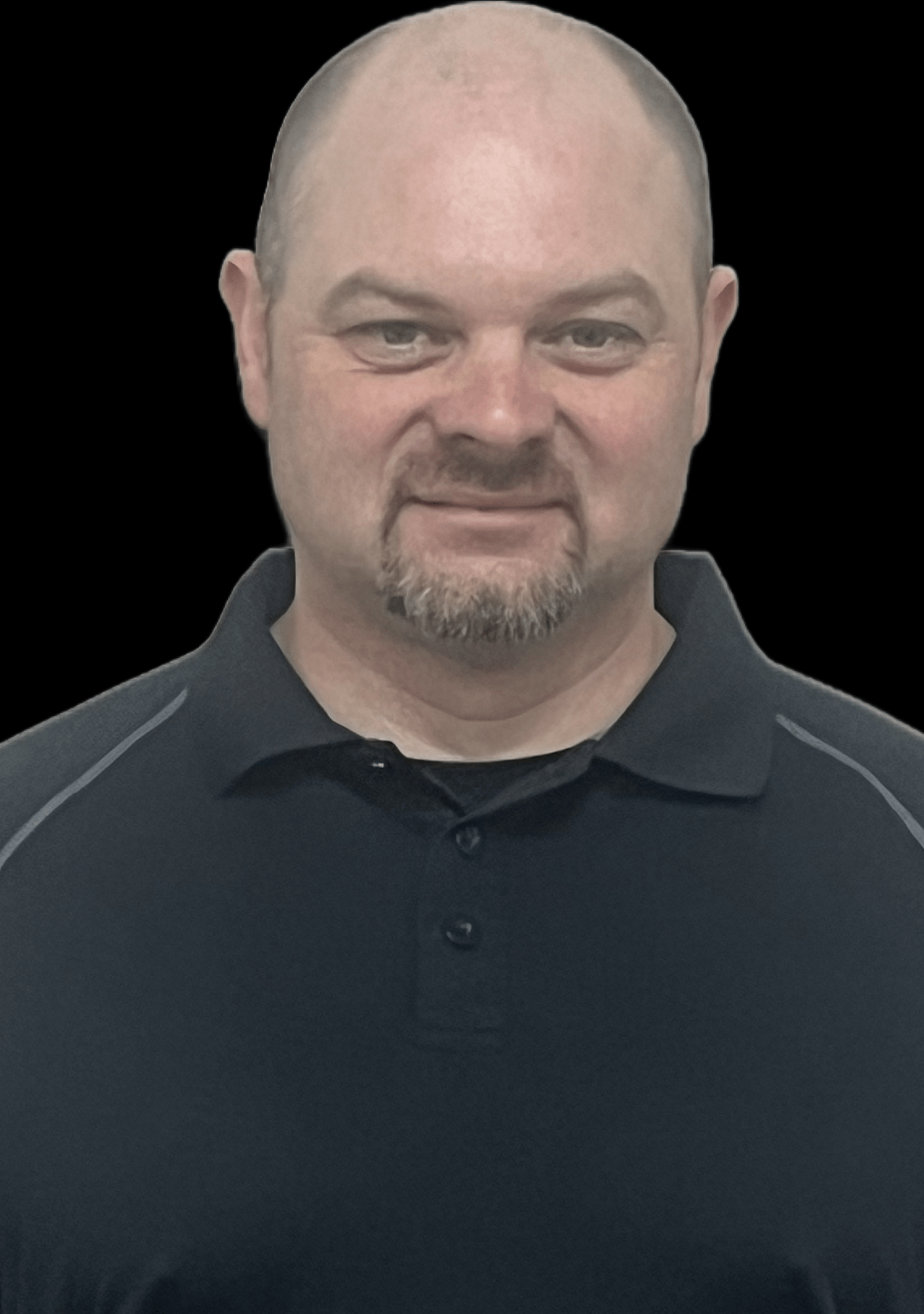 A man with a shaved head and a goatee smiles while wearing a black polo shirt with gray accents.