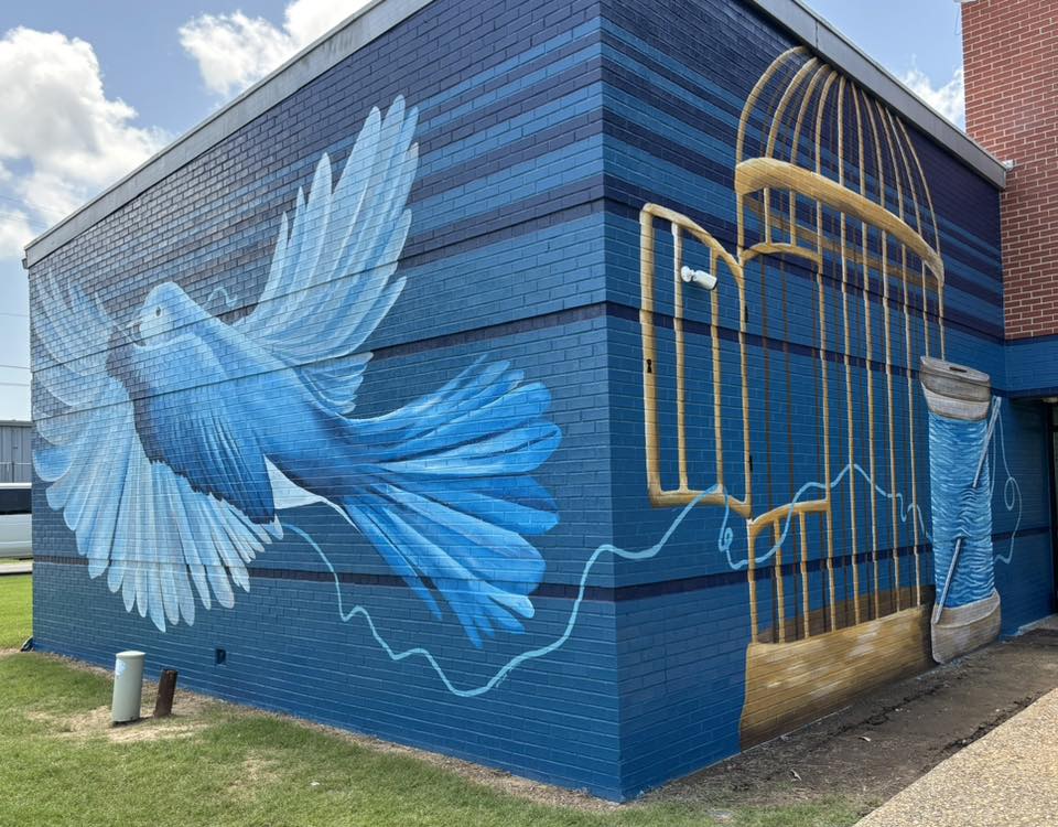 Corner View of a Mural with a blue bird and a cage with a spool of thread
