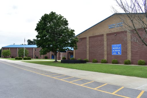1. A large brick building featuring a prominent blue sign displayed on its facade. 2. A substantial brick structure adorned with a blue sign prominently positioned on the exterior. 3. A sizable brick building showcasing a blue sign affixed to its front.