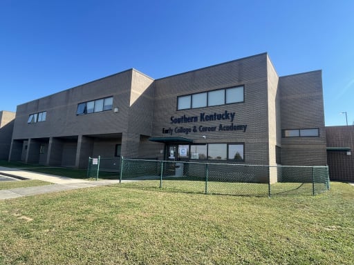 1. The front view of the school building, showcasing its architecture and entrance area. 2. A clear image of the school's facade, highlighting the entrance and surrounding landscape. 3. The exterior of the school building, featuring the main entrance and architectural details.