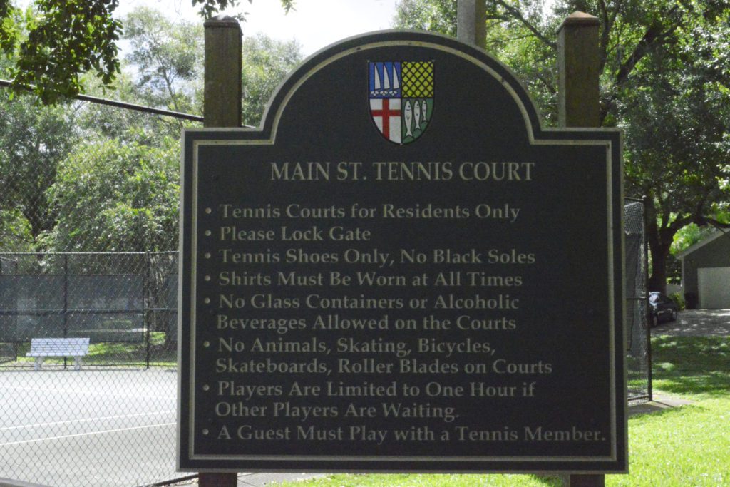 A sign at the Main St. Tennis Court outlining rules and regulations for court use, including dress code and restrictions on animals and beverages.