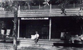 A person sitting on a bench in front of a building with a sign that reads 'UNDERGROUND' in black and white.