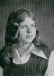 A black and white portrait of a young girl with long hair, wearing a collared shirt and a dark vest, looking thoughtfully to the side.