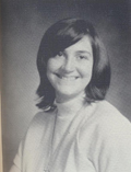 A black and white portrait of a smiling young woman with shoulder-length hair, wearing a light-colored sweater.