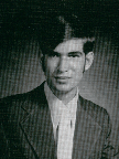 A black and white portrait of a young man with dark hair styled in a side part, wearing a suit and tie, looking directly at the camera.