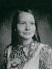 A black and white portrait of a young woman with long hair, wearing a patterned blouse, set against a textured background.