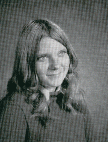 A black and white portrait of a young woman with long, wavy hair, smiling softly at the camera.
