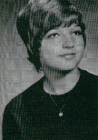 A black and white portrait of a young woman with short hair, wearing a dark top and a necklace, looking slightly to the side with a neutral expression.