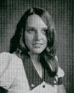 A black and white portrait of a young woman with long hair, wearing a collared shirt, looking slightly to the side with a neutral expression.