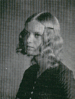 A black and white portrait of a young woman with wavy hair, looking to the side with a serious expression.