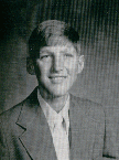 A black and white portrait of a young man with short hair, wearing a suit and tie, smiling at the camera.
