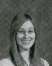 A black and white portrait of a young woman with long hair and glasses, smiling at the camera.