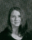 A black and white school portrait of a young woman with long hair, wearing a dark top and smiling softly at the camera.