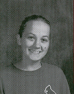 A smiling young girl with light brown hair, wearing a dark shirt with a logo, poses against a textured background.