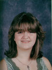 A school portrait of a young woman with medium-length brown hair and bangs, wearing a green top, smiling against a dark blue background.