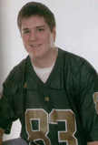 A young man wearing a green sports jersey with the number 83, smiling while seated against a plain white background.