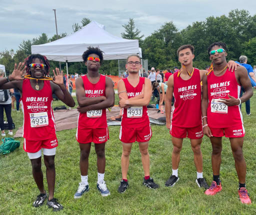 crosscountry team posing on field for photo