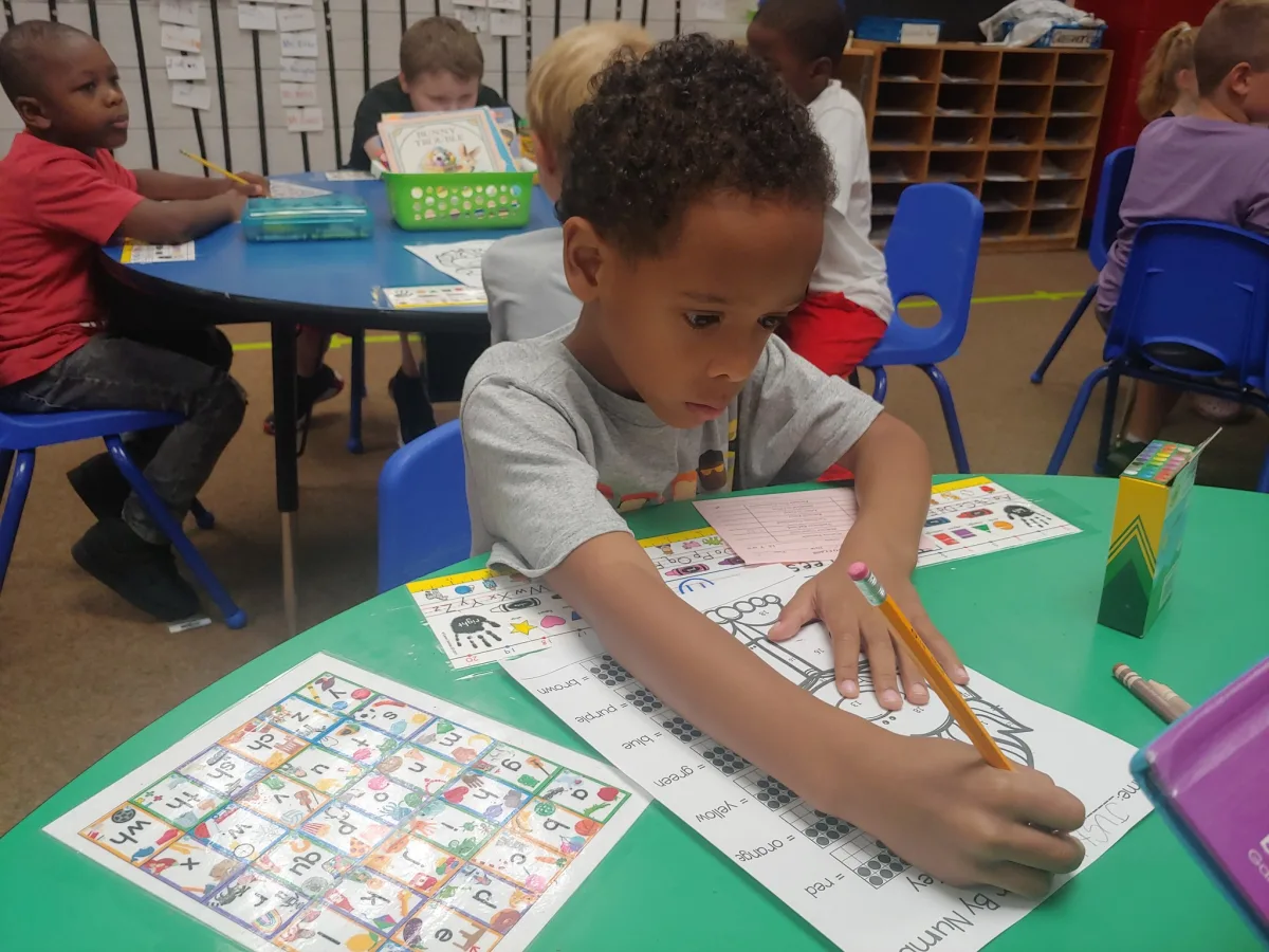 kid answering an activity at classromm table