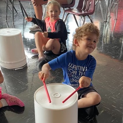 male student playing drums on a bucket