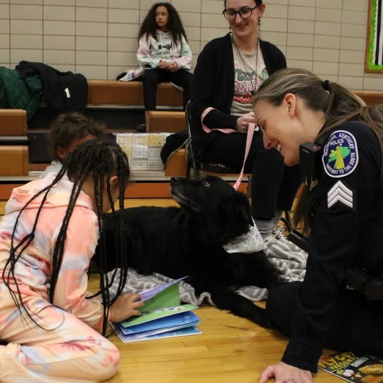 student reading a book to a police officer