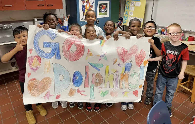 kids with a sign that its read go dolphines