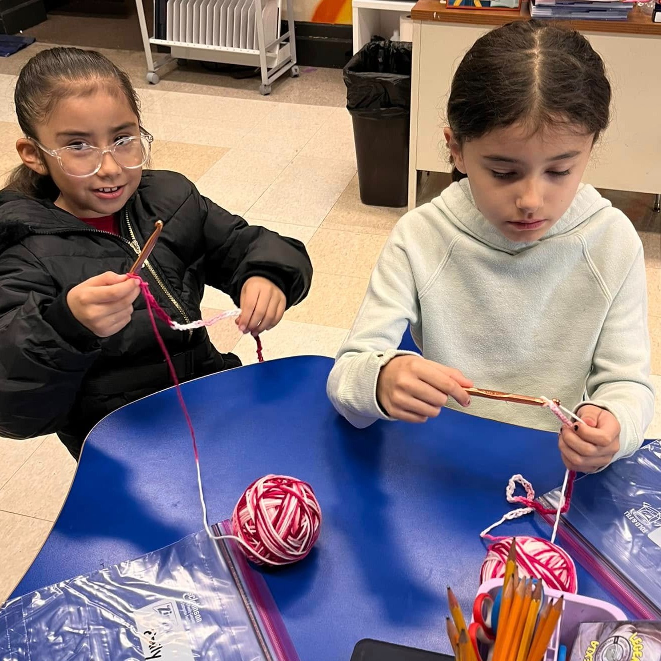 Two young girls learning to crochet