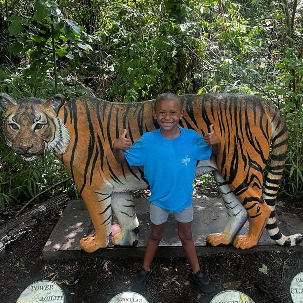 male student posing with a tiger statue at the zoo