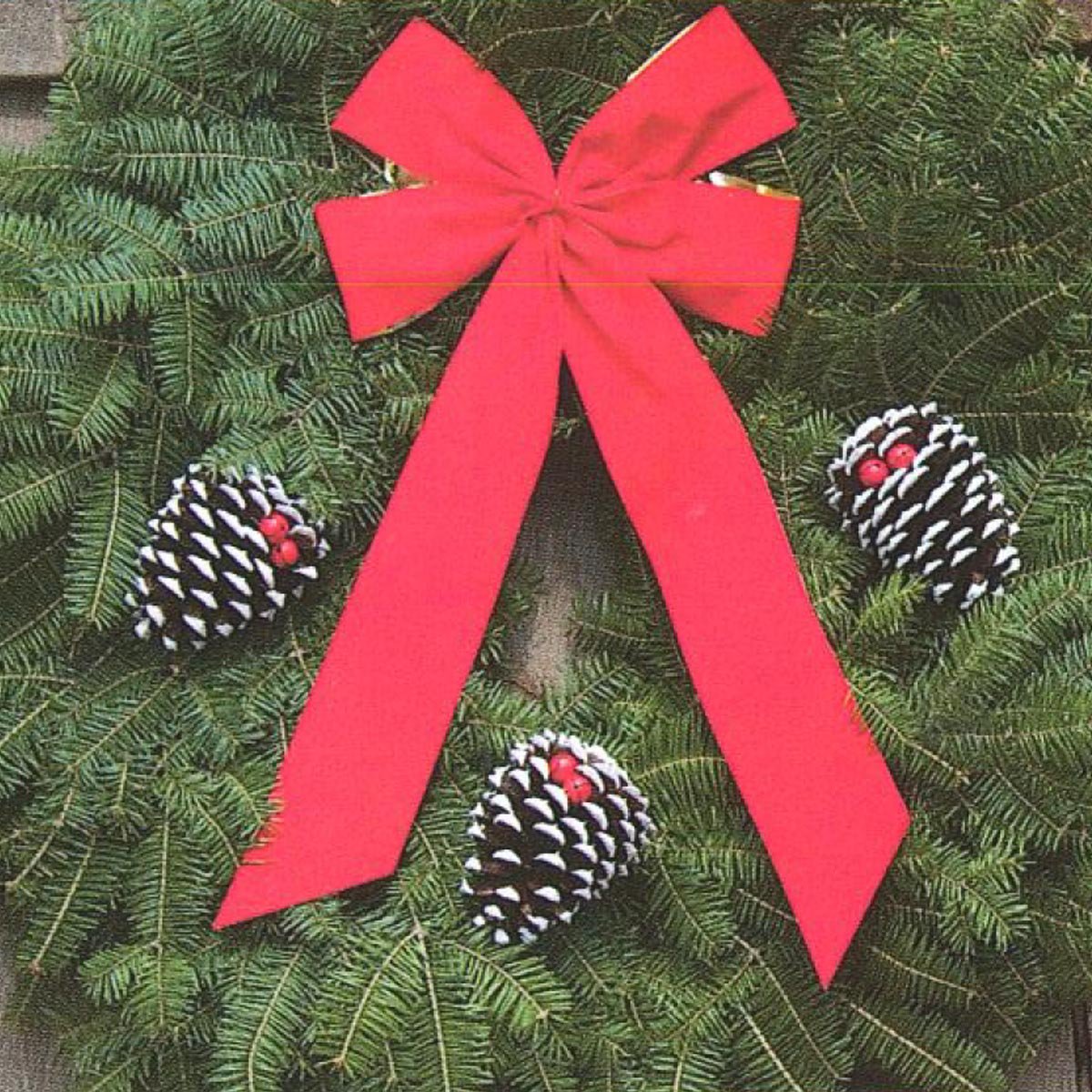 A festive green wreath adorned with a large red bow and three decorated pine cones, featuring white tips and red accents.