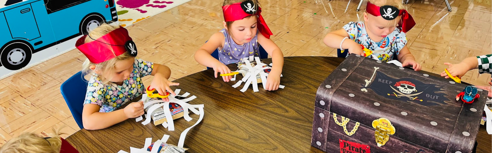 preschool students dressed as pirates cutting paper for a project