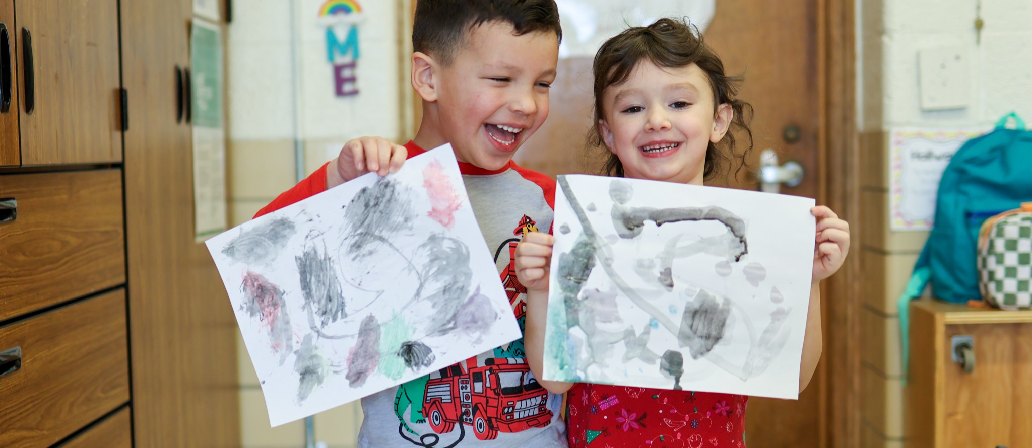 two kids smiling holding their paintings