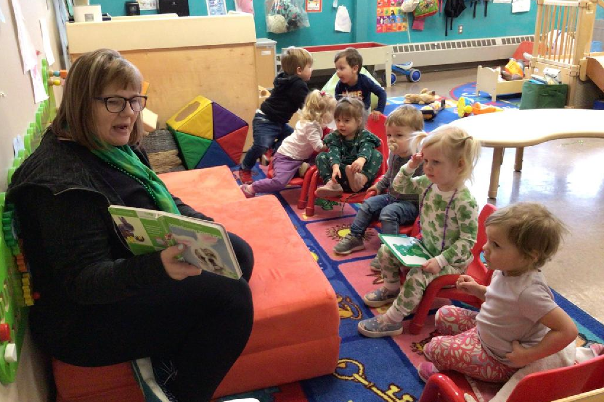 Teacher reading a picture book in front of a group of preschoolers.