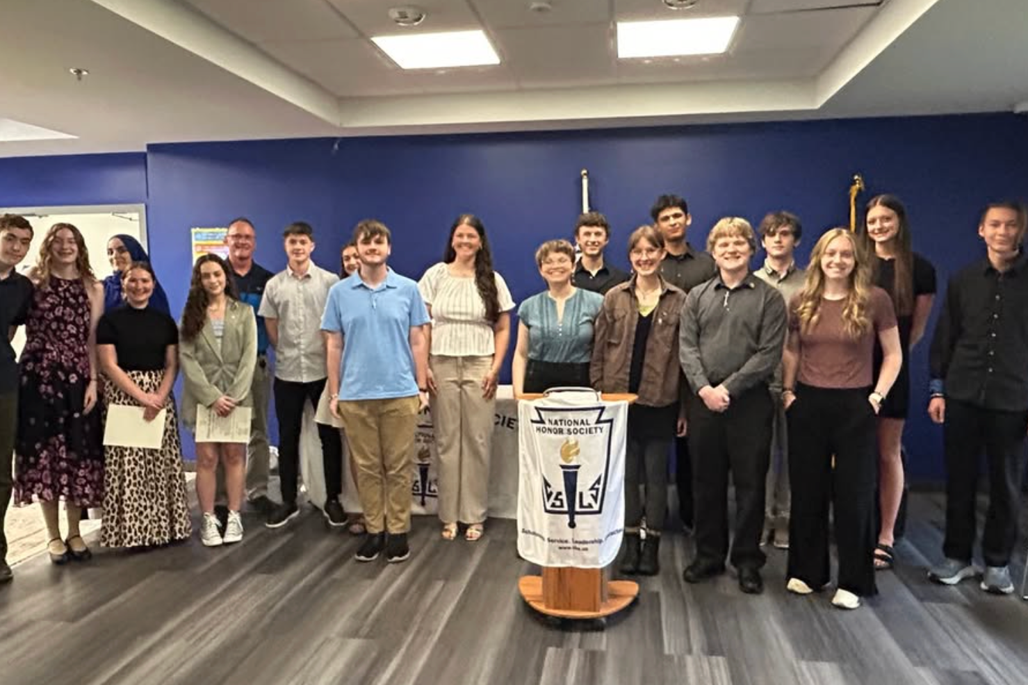 A group of students stand at podium smiling to take a picture