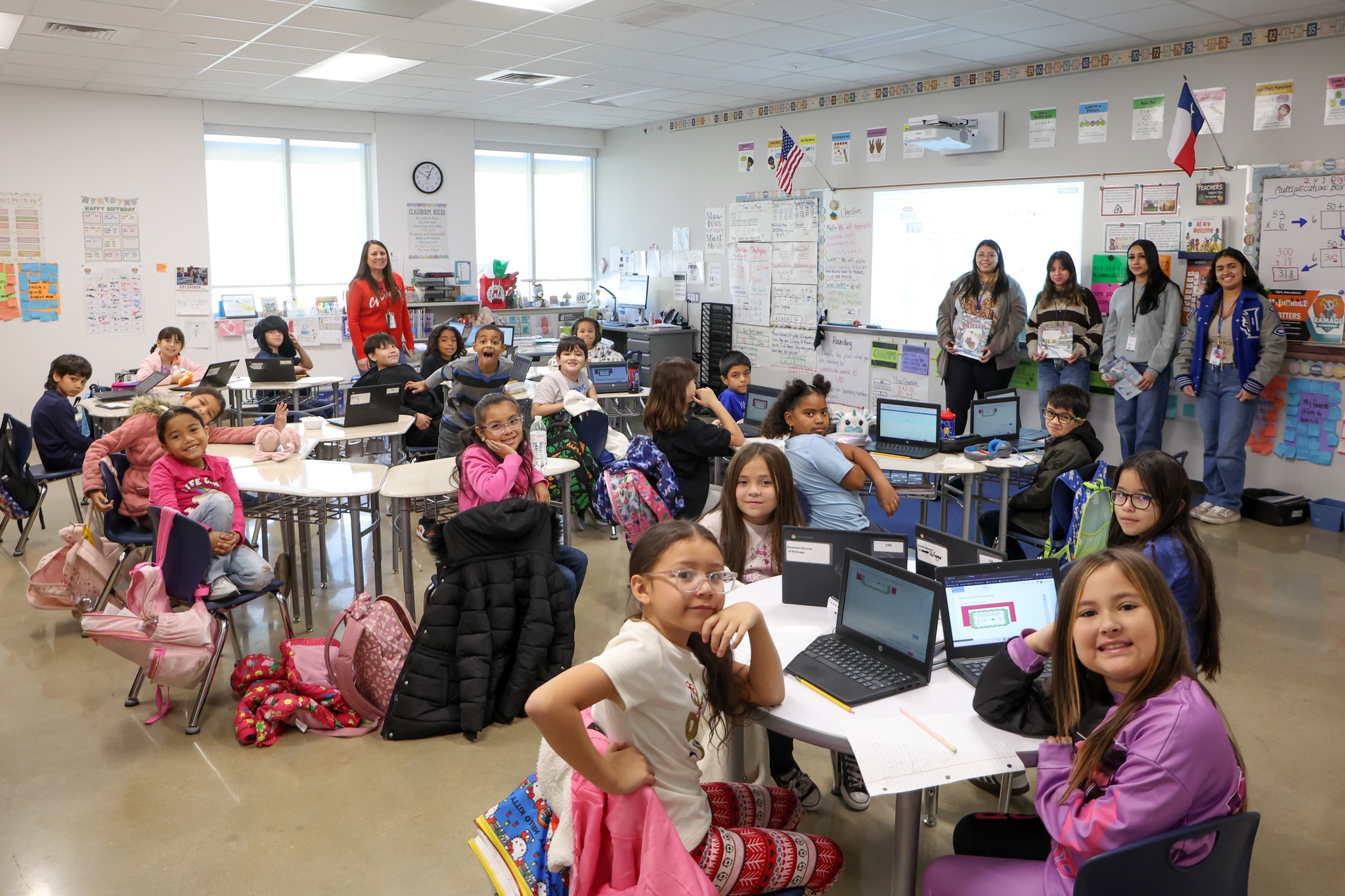 A classroom full of elementary students with high school students presenting to the class