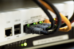 Close-up view of a network device with multiple connected cables and illuminated ports, indicating active connections.