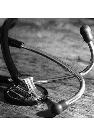 Close-up of a stethoscope resting on a wooden surface, highlighting its sleek metallic head and black tubing.