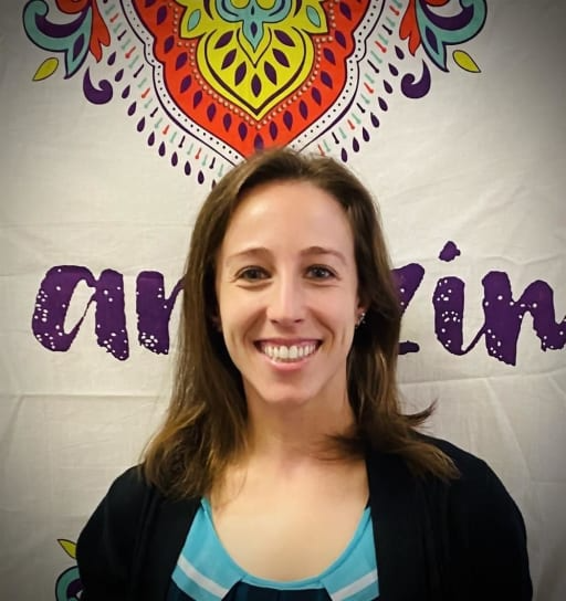 A woman stands confidently in front of a banner displaying the word "amazing," exuding positivity and enthusiasm.