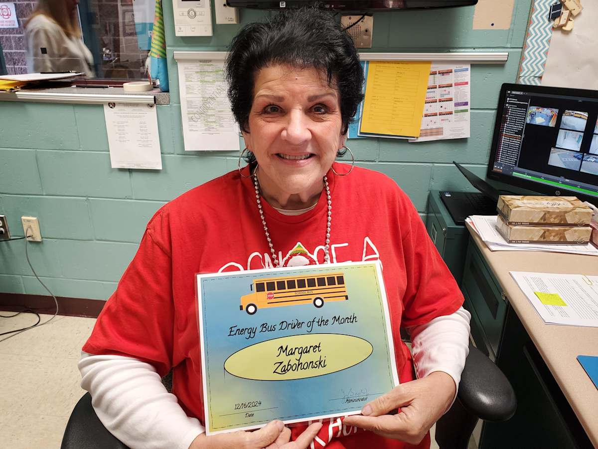 A woman in a red shirt proudly displays her certificate, showcasing her achievement and joy.