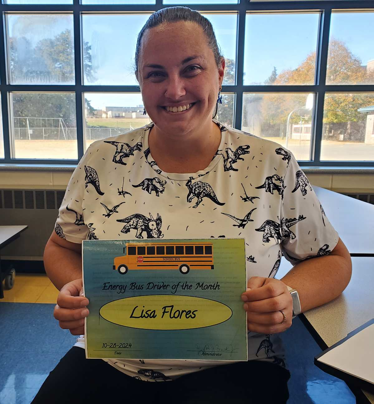 A woman proudly displays a sign reading "lisa flores" in a public setting.