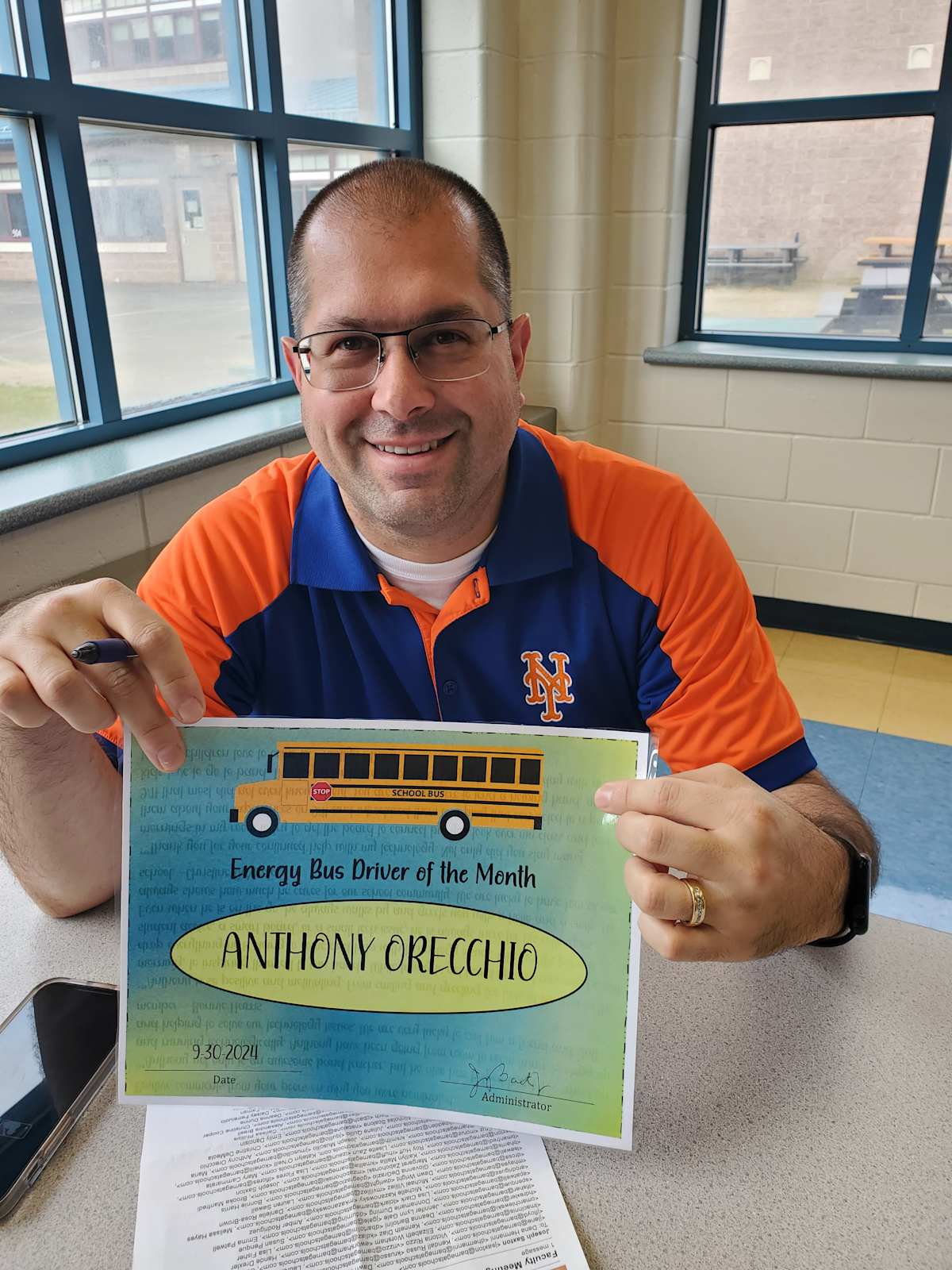 A proud man displays a certificate, celebrating his son's achievement with a joyful smile.