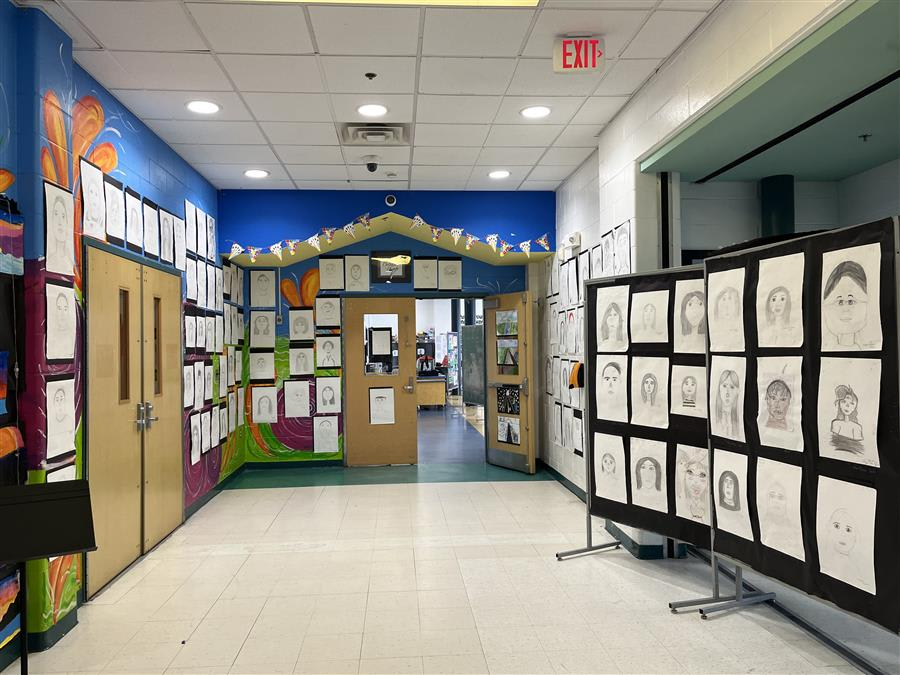 A hallway adorned with framed pictures on the walls and a colorful poster board displayed prominently.