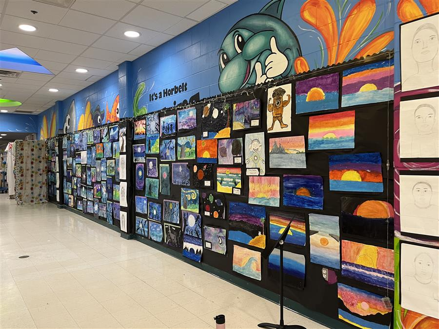 A vibrant hallway adorned with numerous colorful paintings lining the walls, creating an inviting and artistic atmosphere.