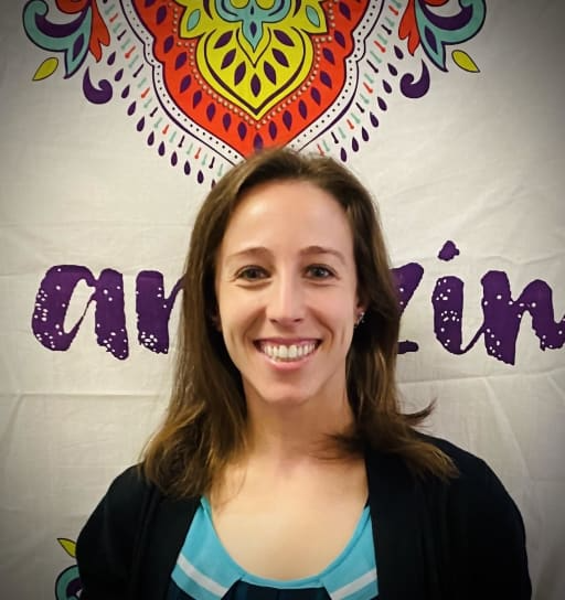 A woman stands confidently in front of a banner displaying the word "amazing," exuding positivity and enthusiasm.