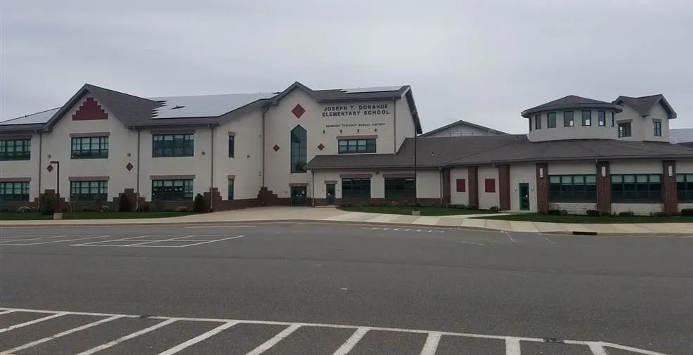 A large white building stands prominently beside a spacious parking lot, showcasing its modern architecture.