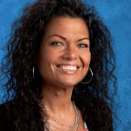  A woman with curly hair stands against a vibrant blue background, exuding confidence and grace