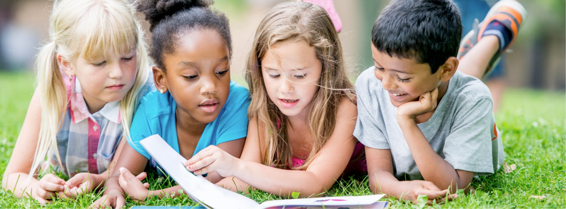 children reading lay down on the grass