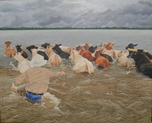 A person in a wide-brimmed hat is wading through water, guiding a group of cows swimming in a river under a cloudy sky.