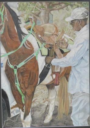 A person in a white outfit is adjusting a saddle on a brown horse, with green straps visible, set against a natural background.