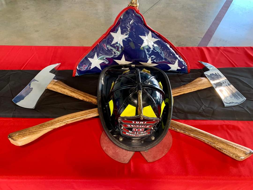 Fire fighter helmet displayed on top of axes with folded memorial American flag. 