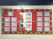 A colorful bulletin board featuring a central quote about reading and learning, surrounded by framed text boxes, all set against a red background with decorative elements.