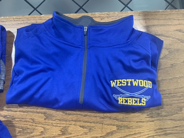 A blue athletic pullover with a half-zip collar, featuring the text 'WESTWOOD REBELS' in yellow on the left side.